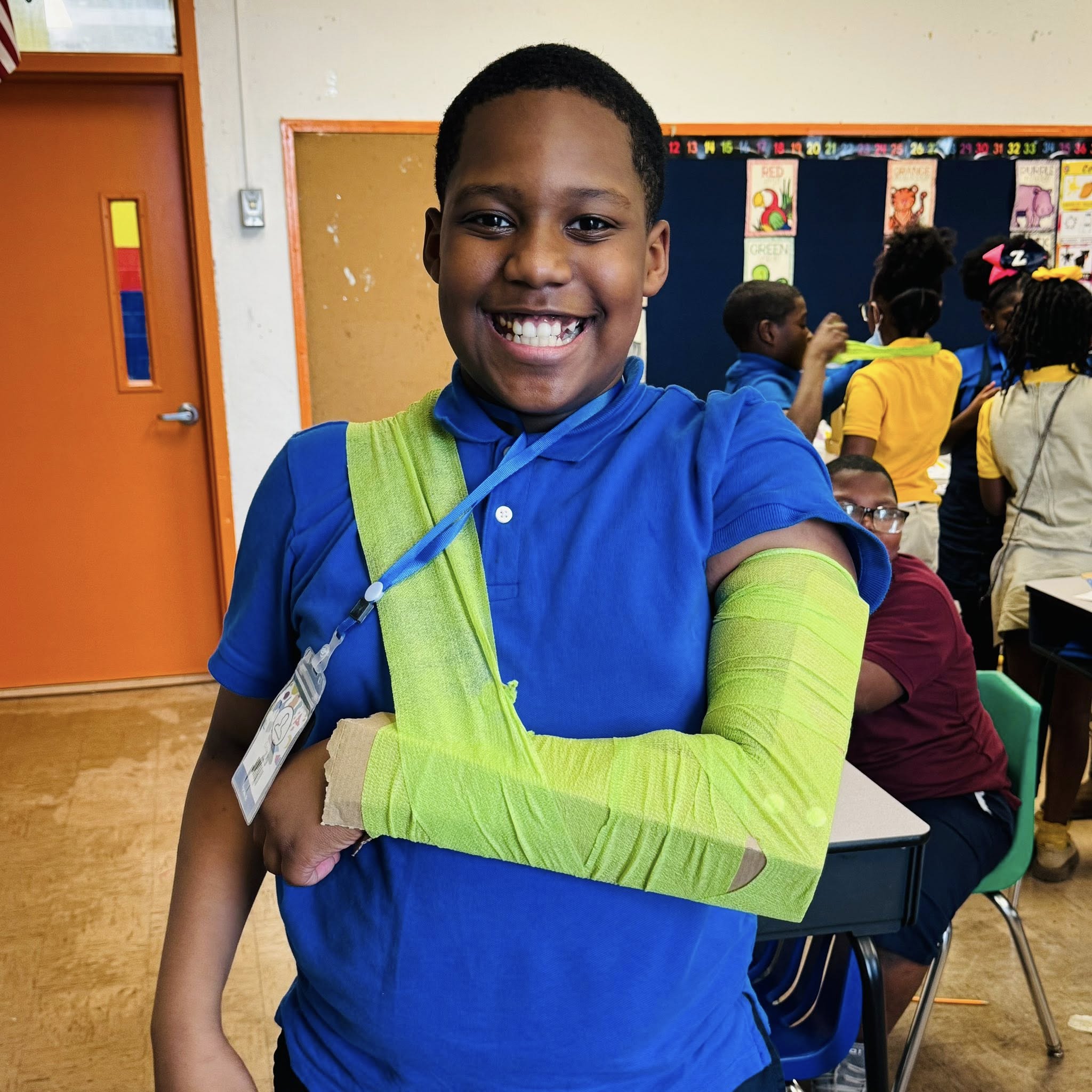 A smiling boy with a homemade splint on his arm.